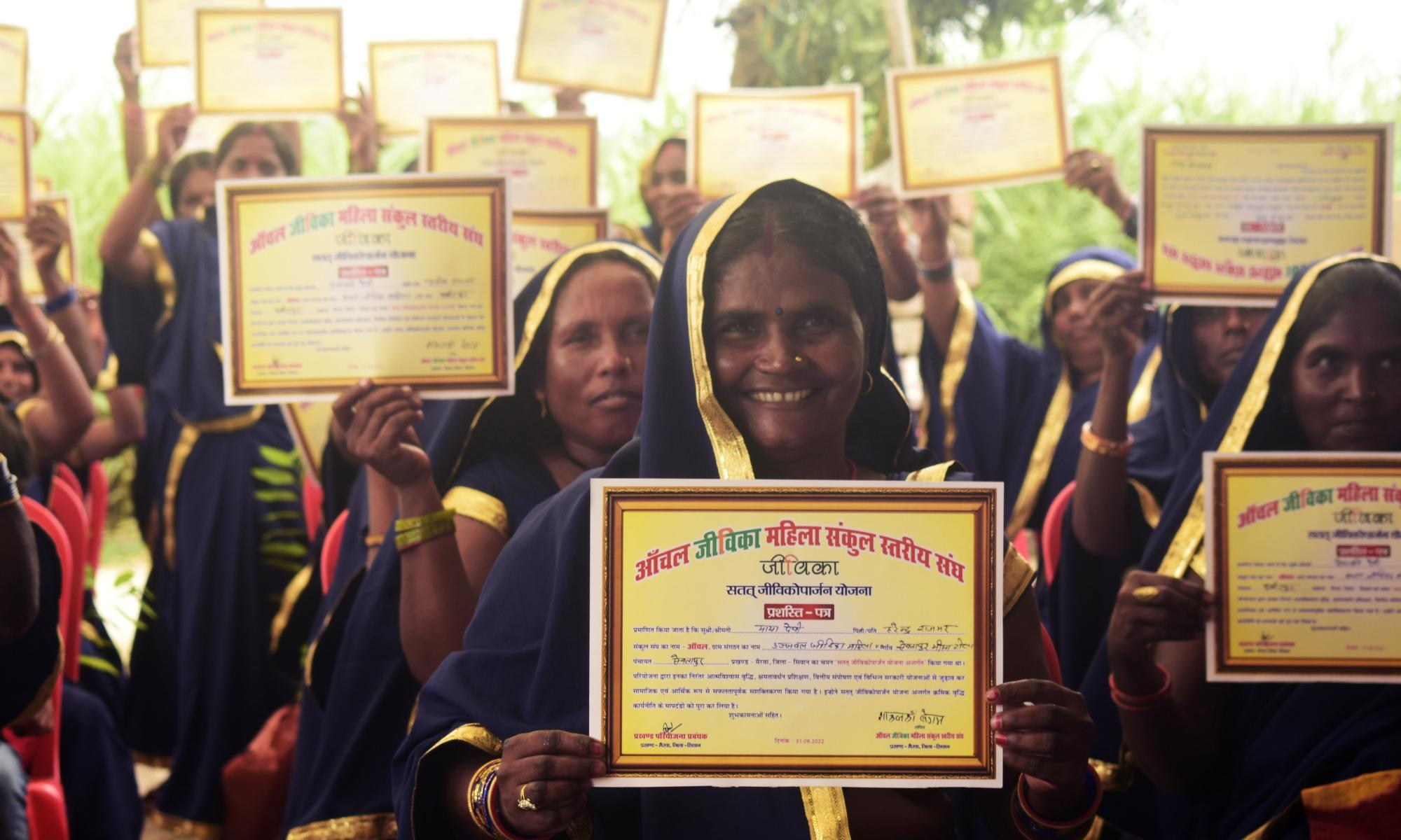Women in India hold up their diplomas
