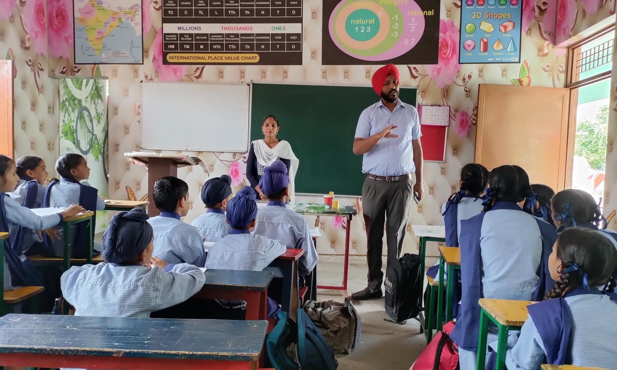 a man and women teaching children in a classroom in india