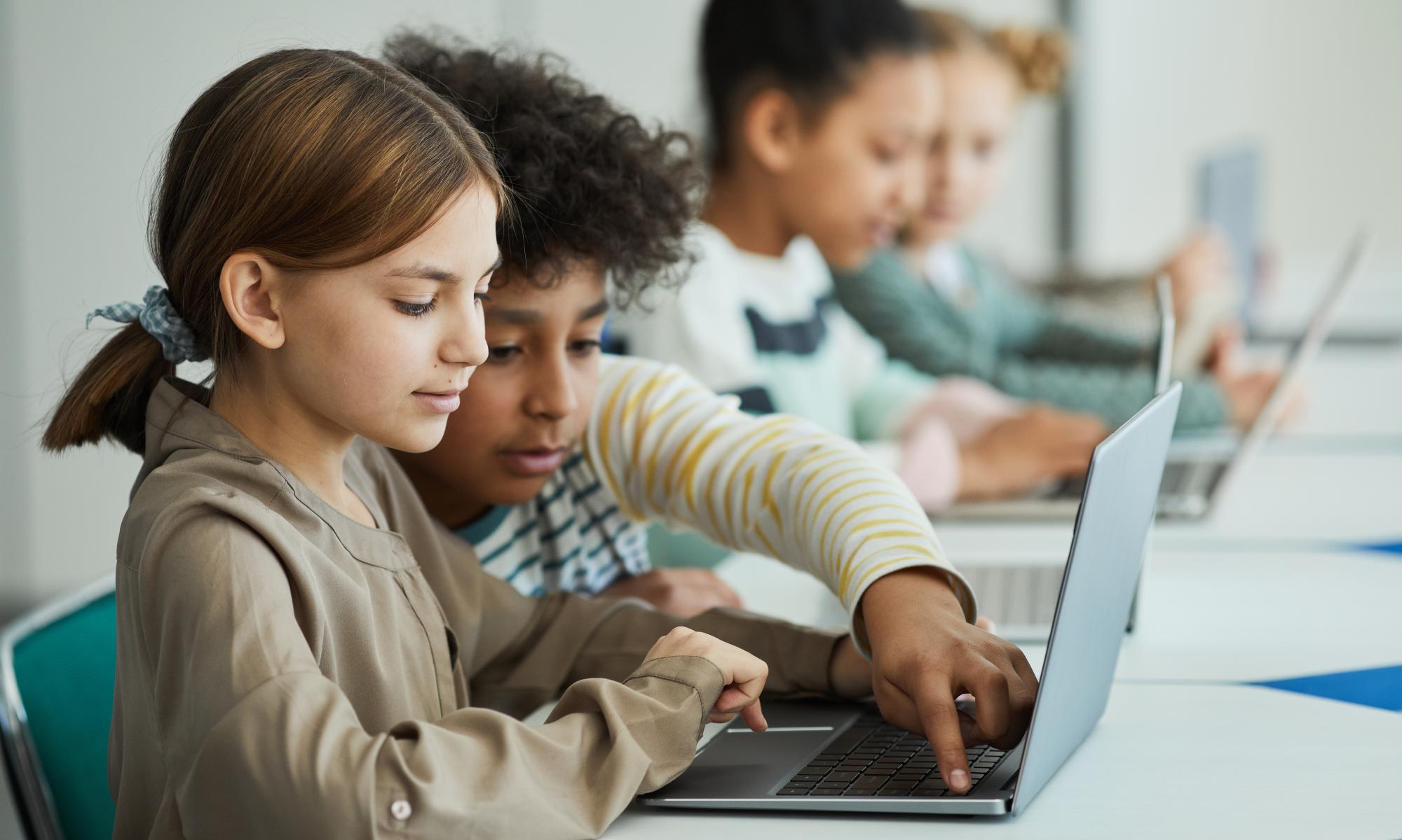 An elementary aged boy and girl looking at computer