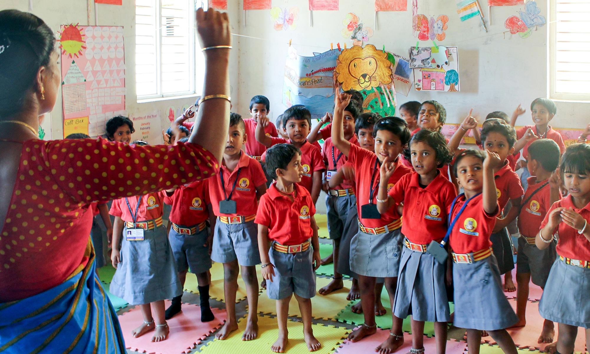 Teacher with a raised hand standing in front a group of elementary students