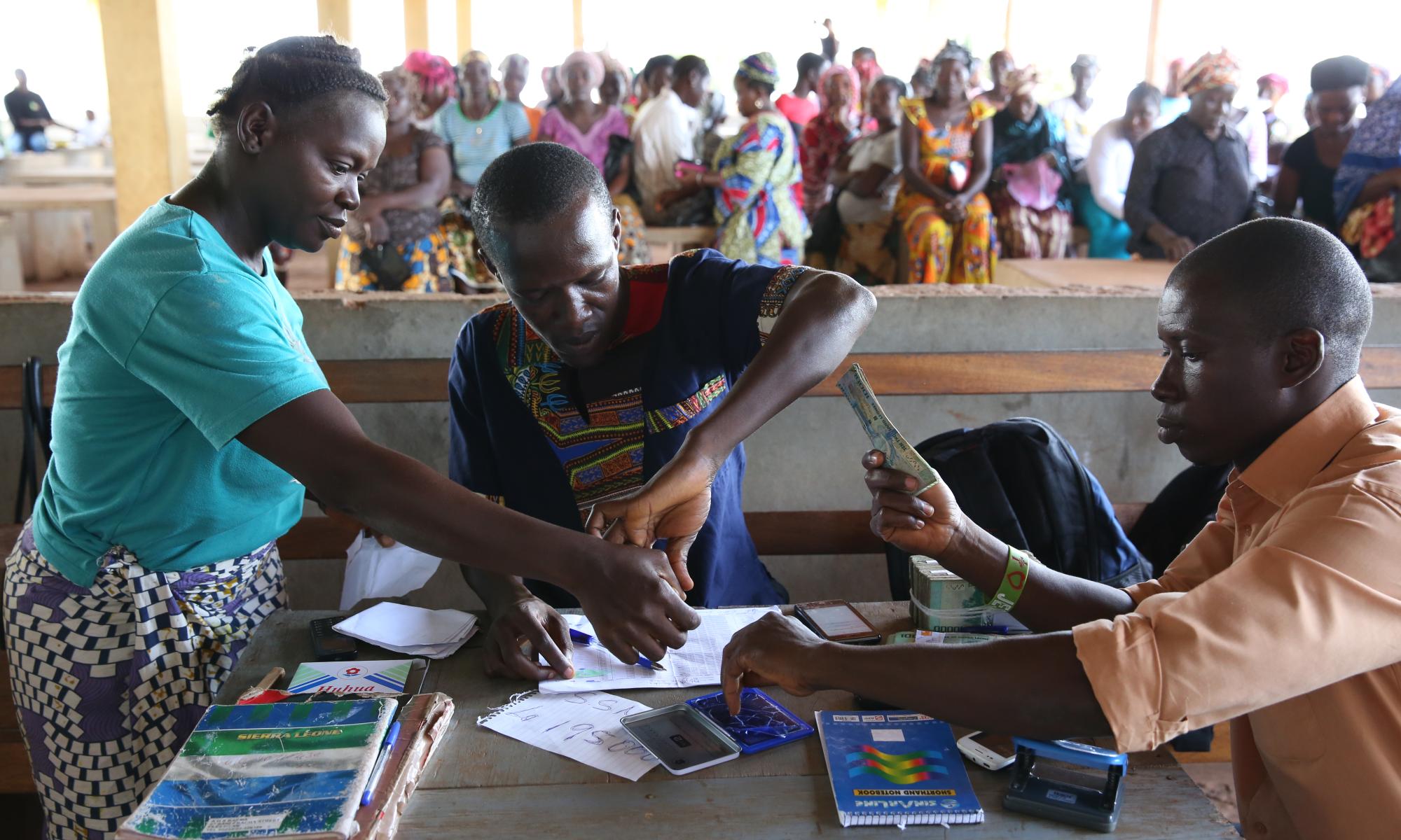 Three people at a table with one person handing over cash.