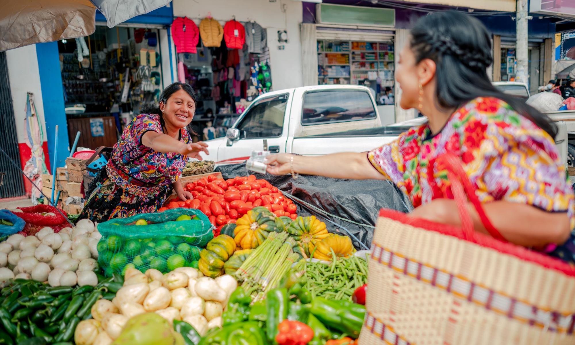 Woman at a market handing cash to a vendor