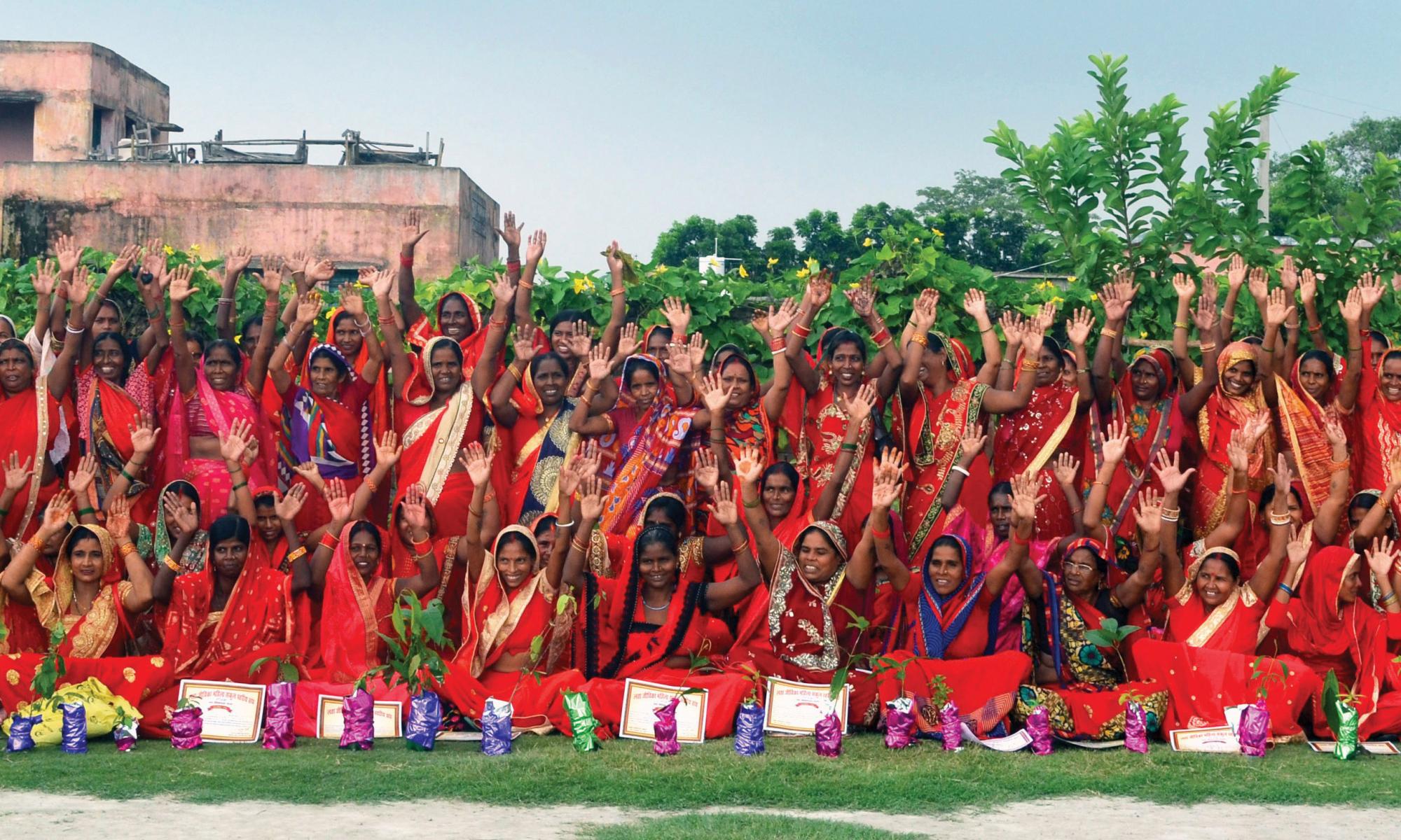Dozens of women posing with their hands in the air celebrating