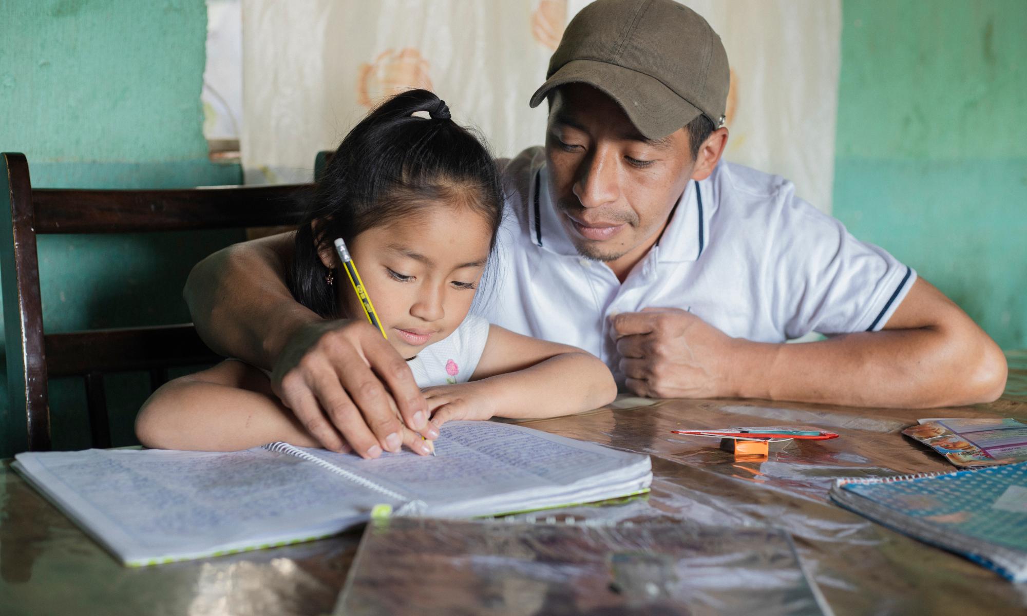 Father and daughter sitting a table doing homework