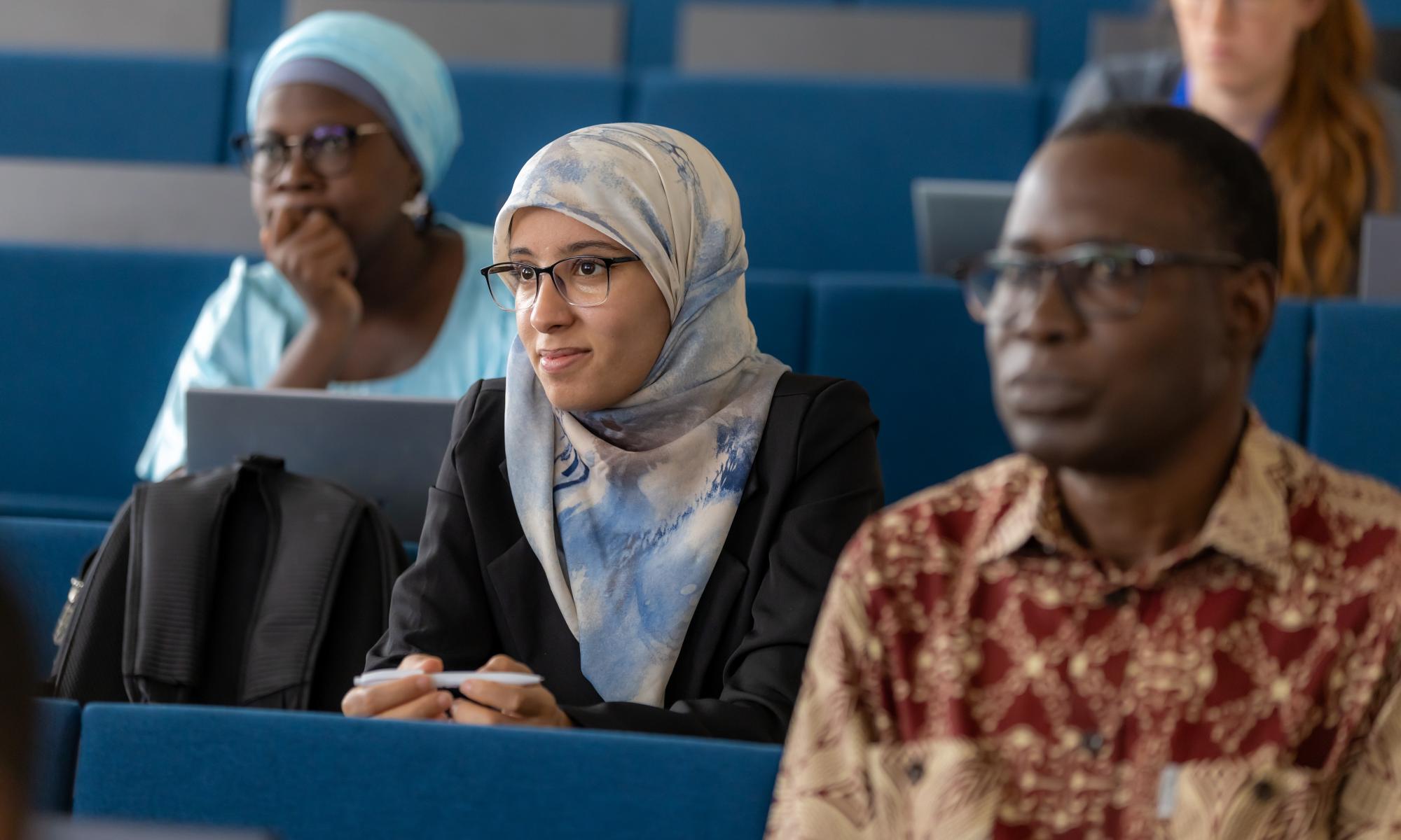 Female student smiles while sitting in a classroom next to other students