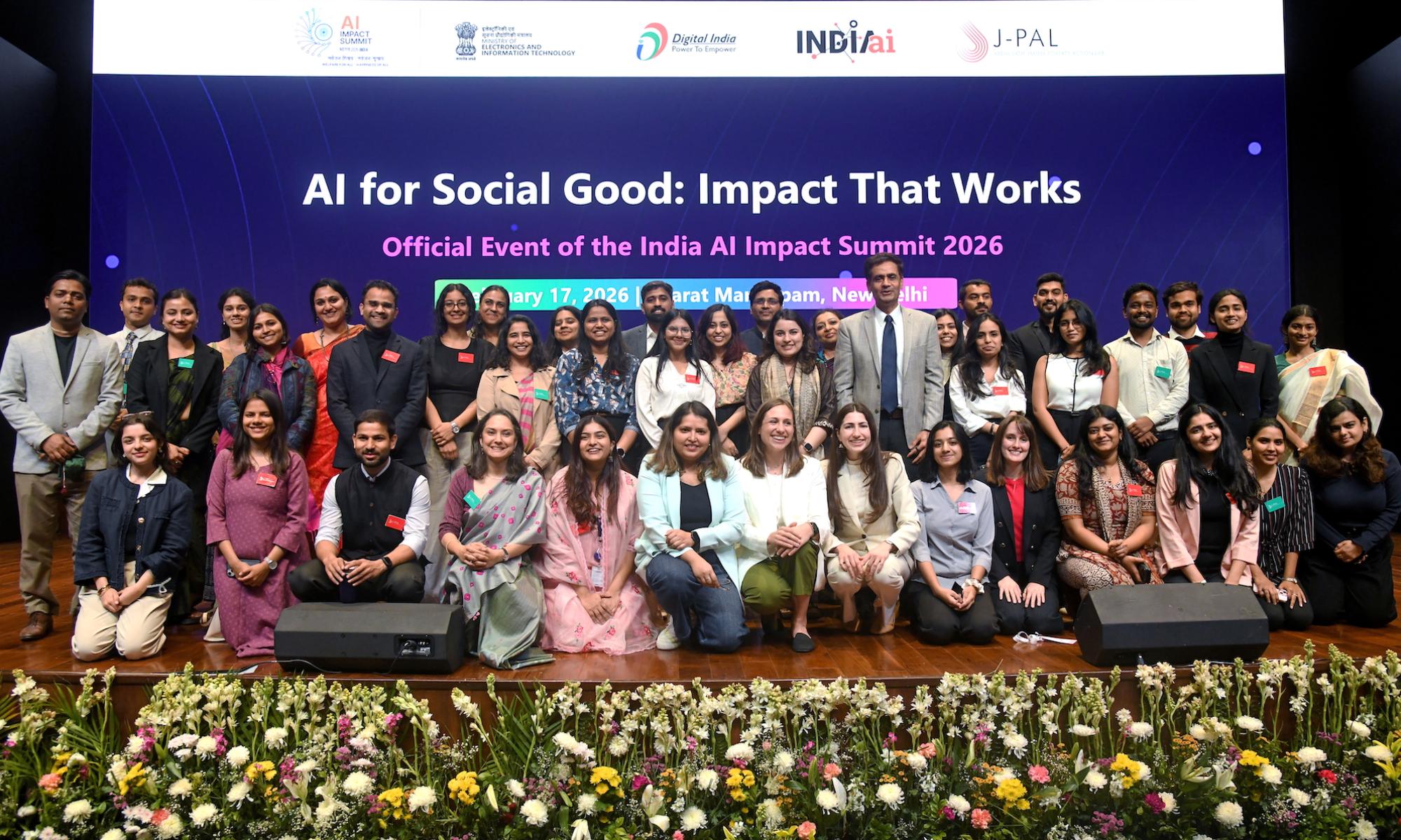 Group photo on main stage at 2026 AI summit in front of digital event backdrop