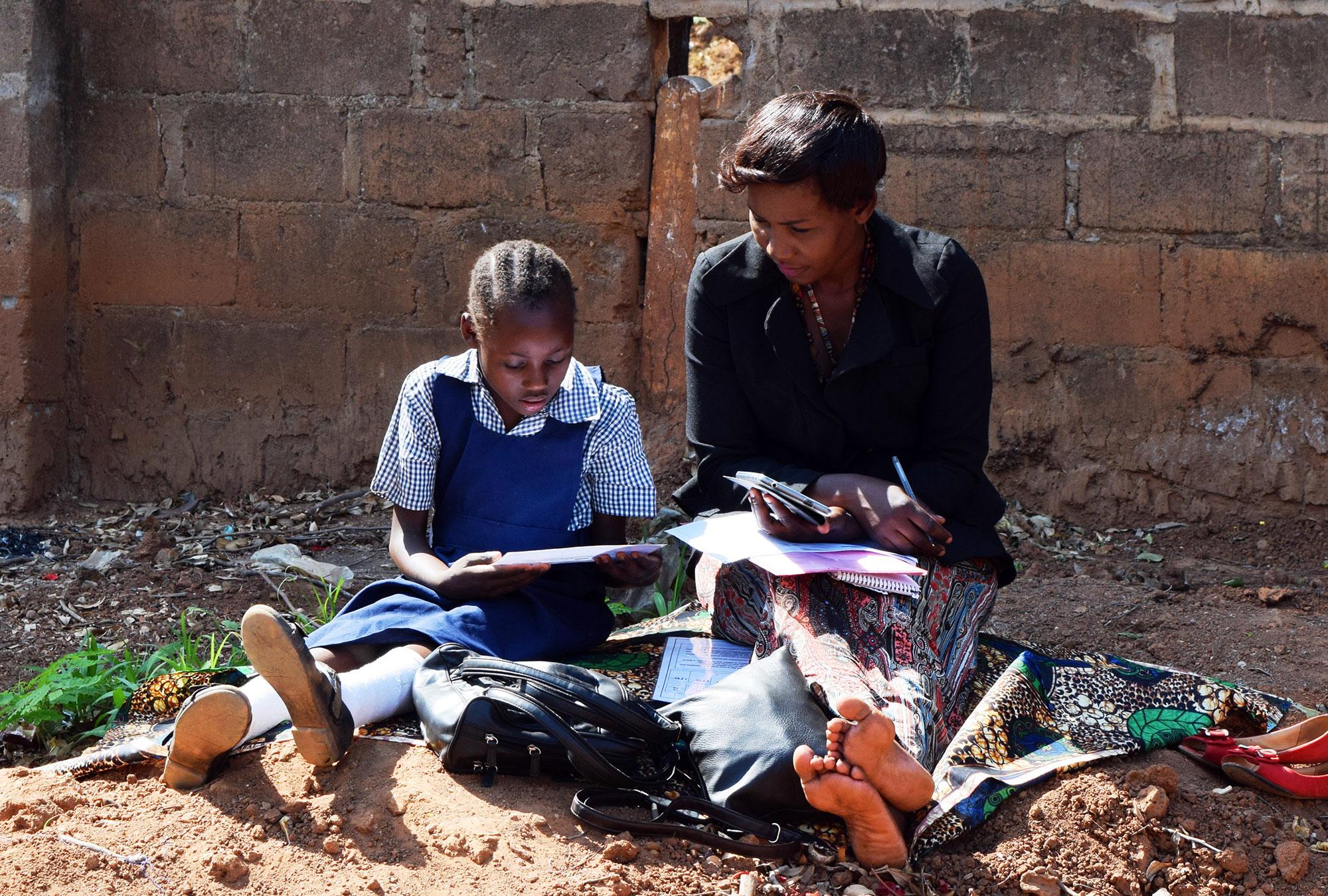 Woman helps a girl with her reading