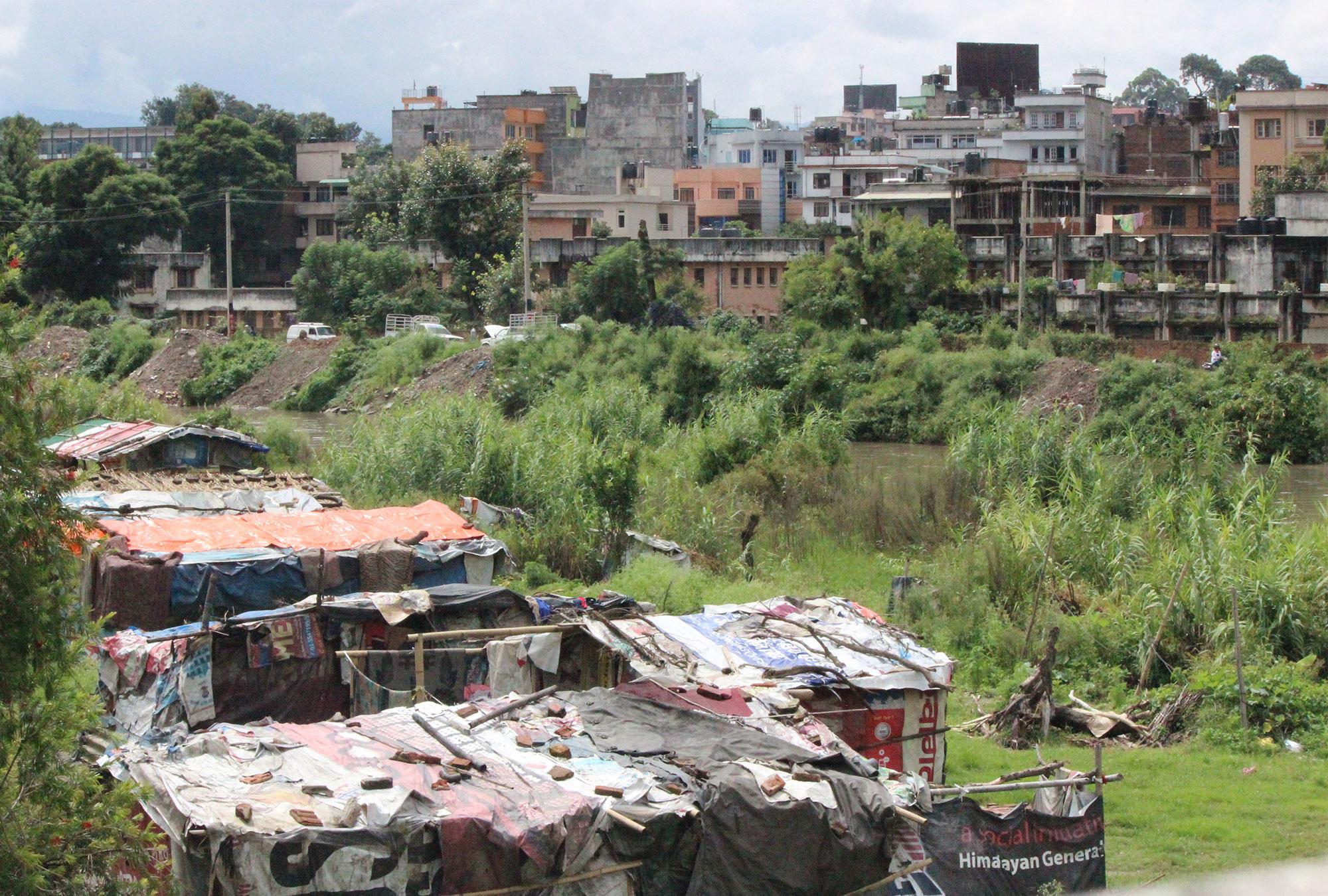 Houses made from tarps and wooden poles on the outskirts of a city