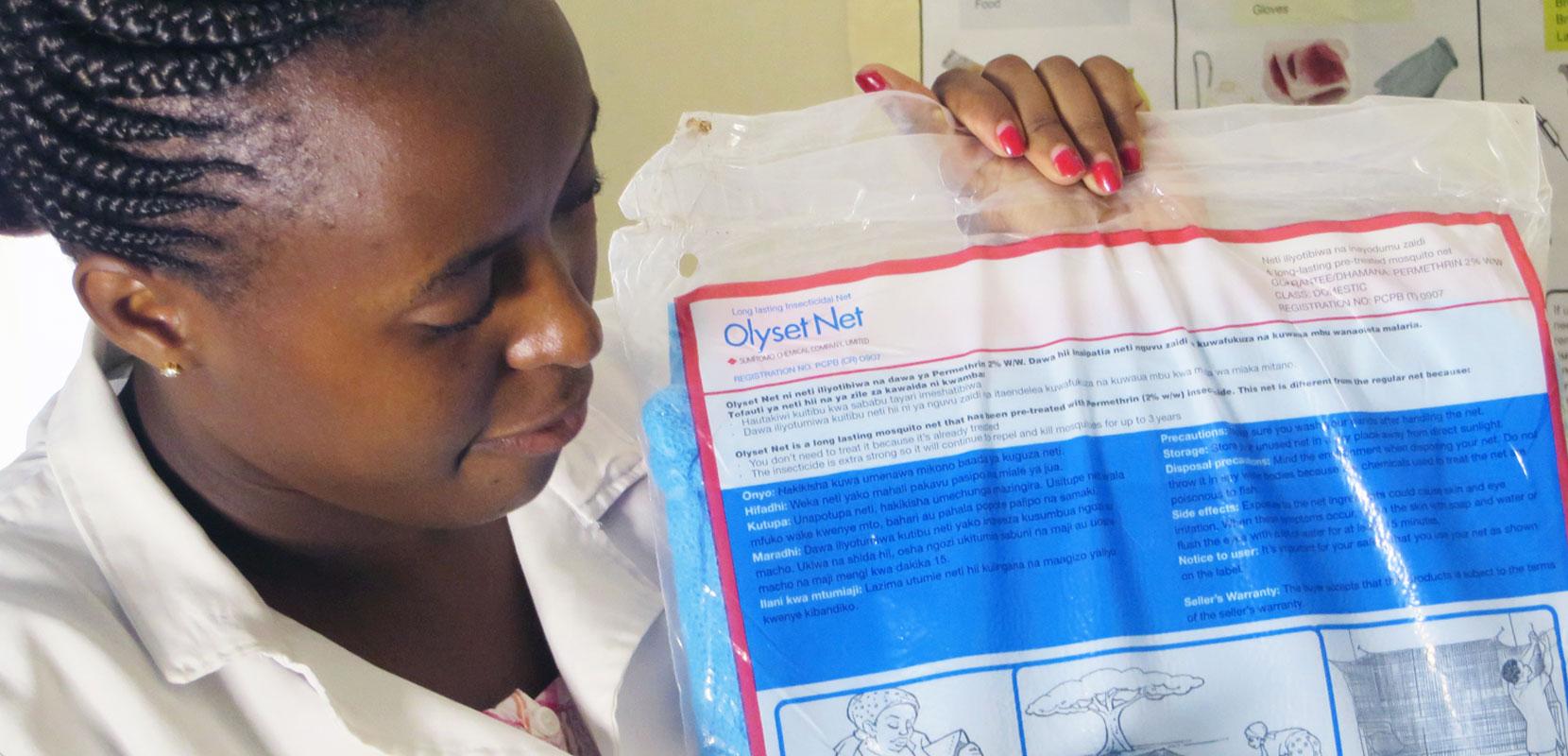 A woman receives a free insecticide-treated bednet at a health clinic in Kakamega County, Kenya.
