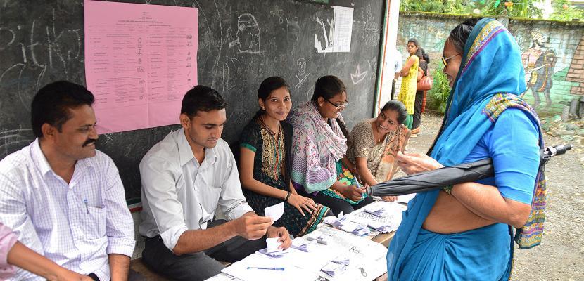 woman approaching group sitting at a table of documents