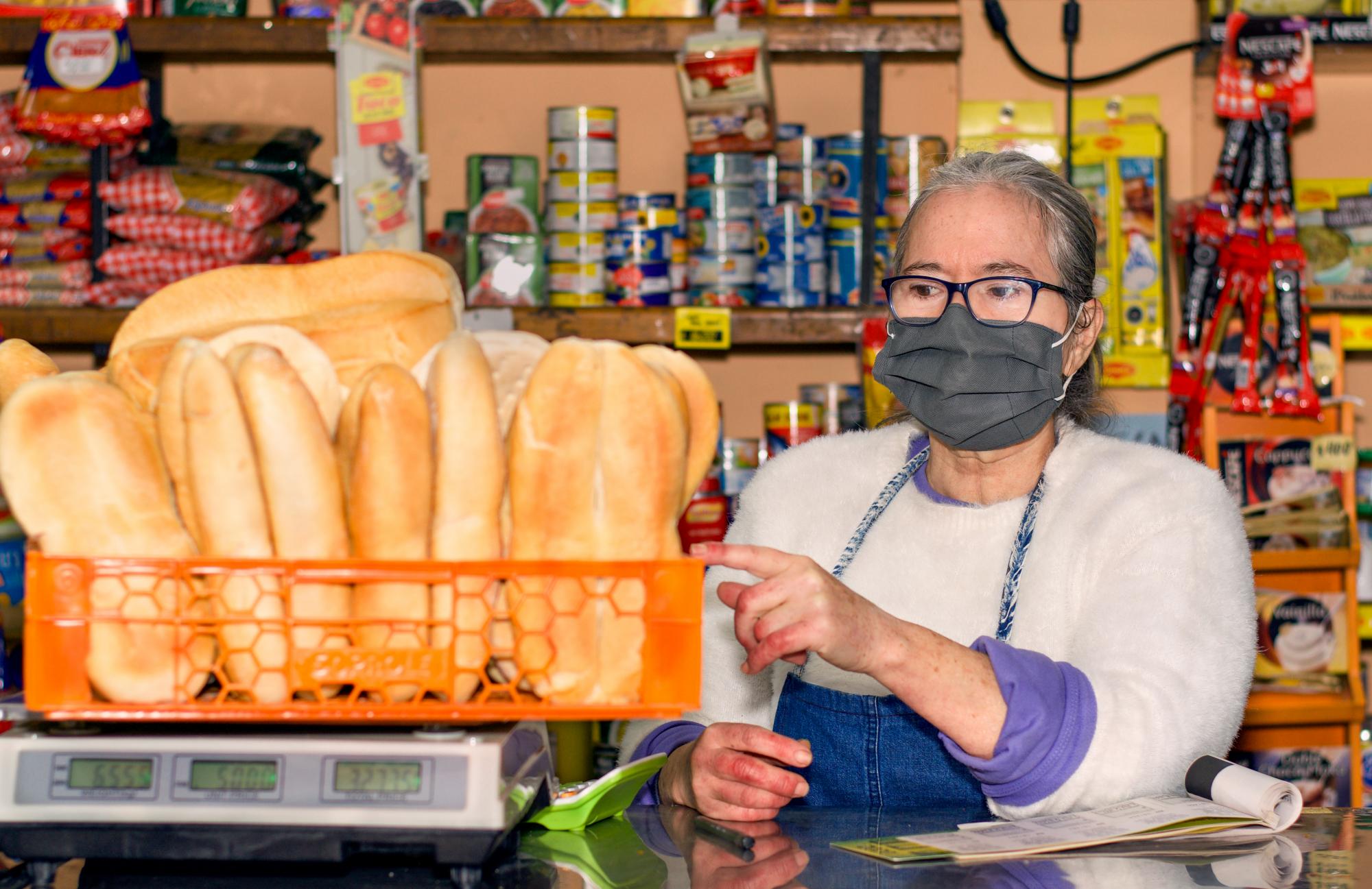 A woman wearing a mask weighs bread in a store