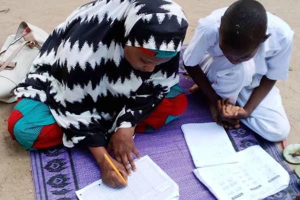 Two children taking an assessment exam on the ground.