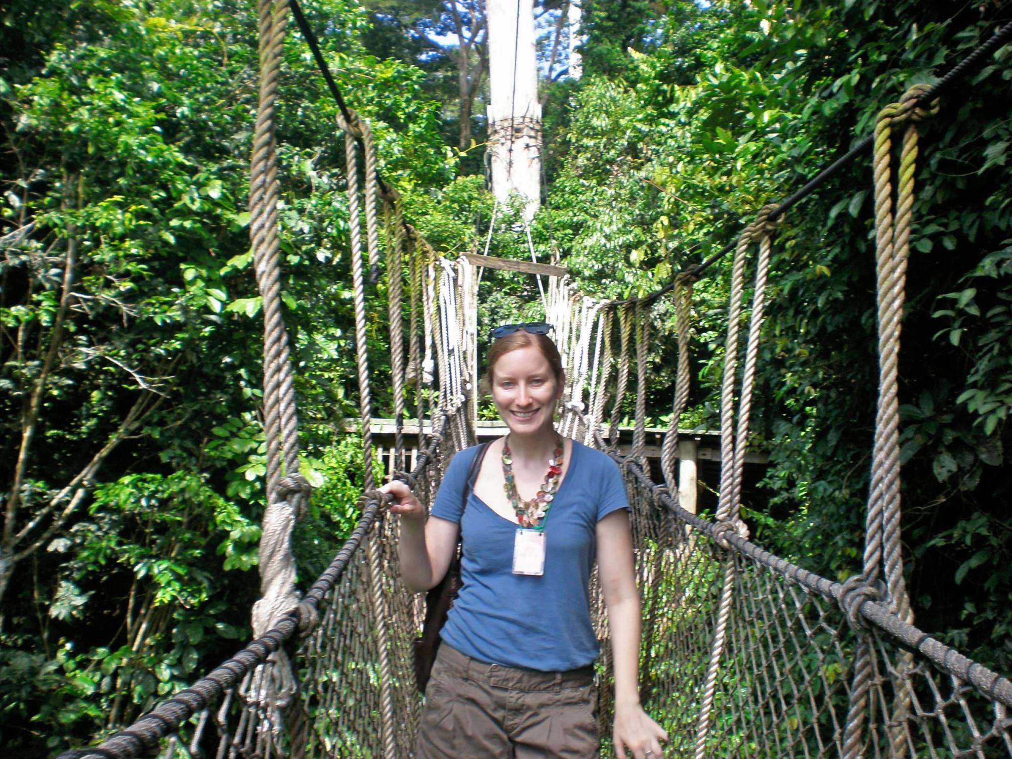 Caitlin Tulloch stands alone on a dangling bridge in a forest