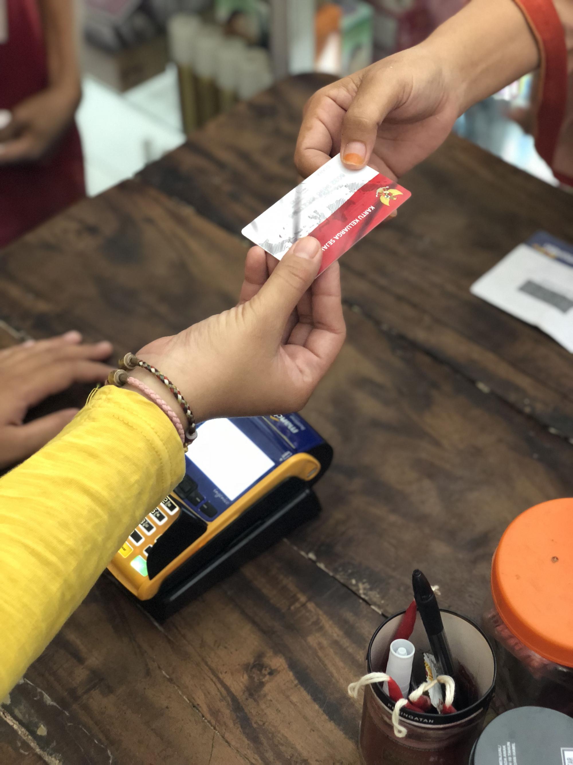 A person hands a card to another person operating a card reader