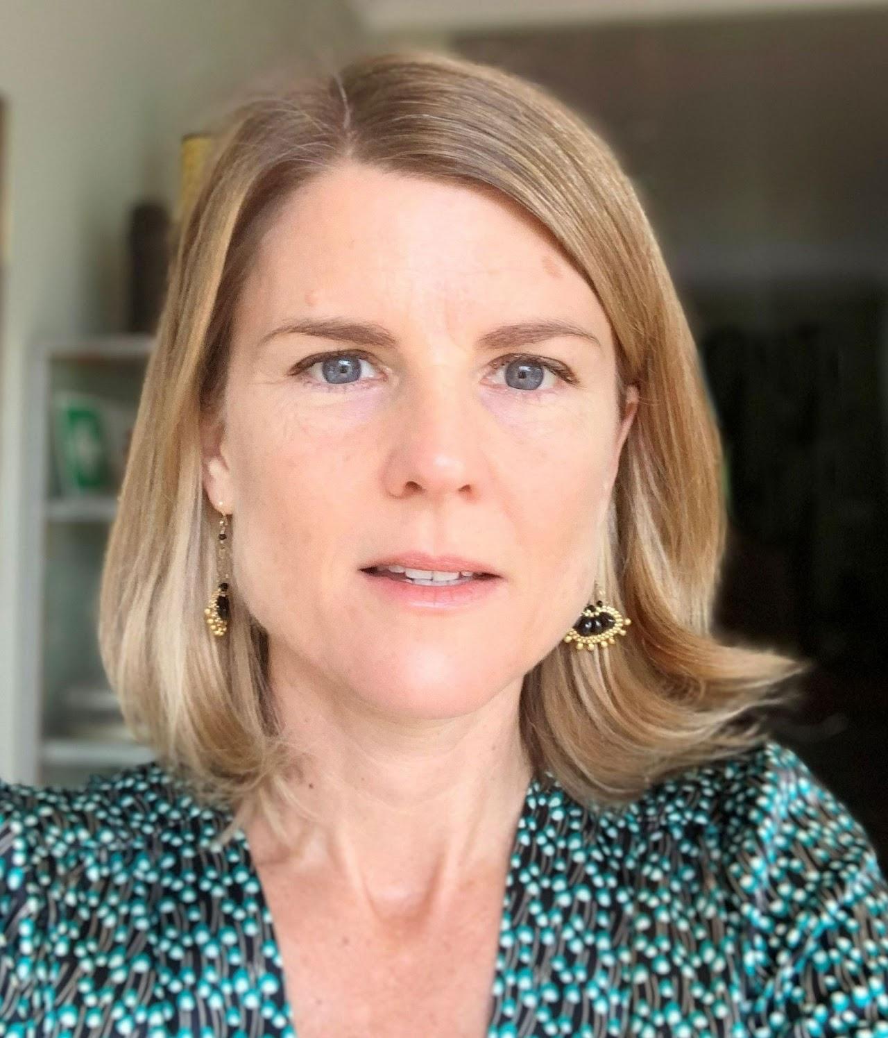 A head shot featuring a photo of Cally Ardington. She is wearing a green shirt and has brown shoulder length hair. 