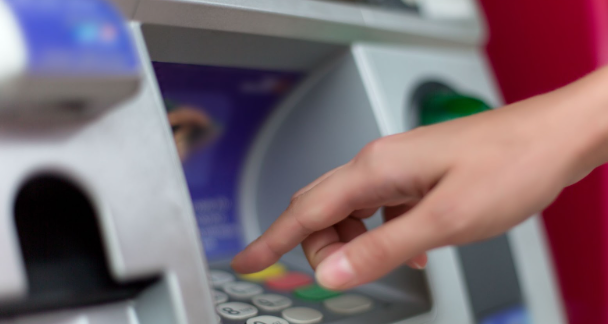 Close up of female hand entering PIN pass code on ATM bank machine keypad