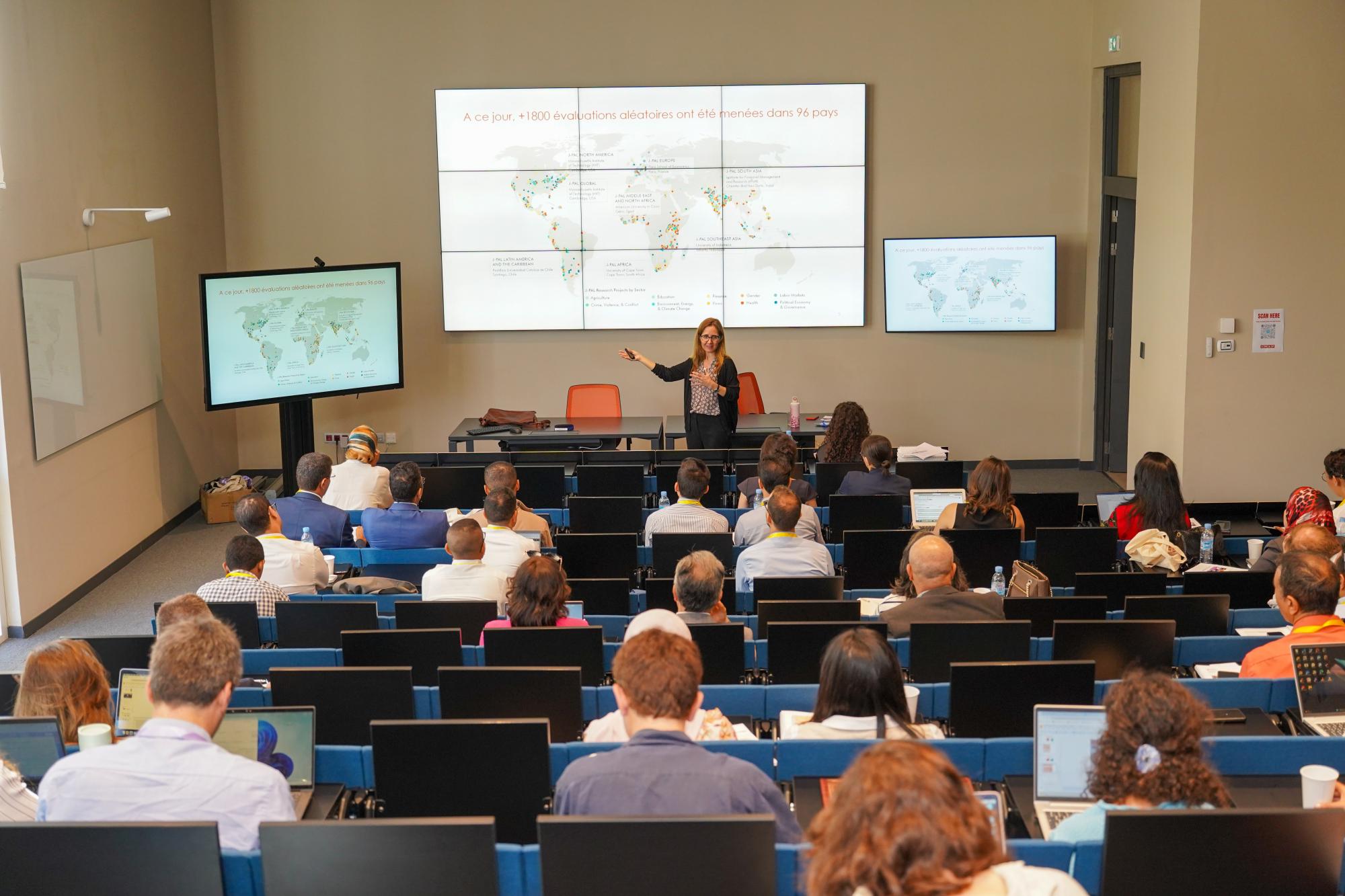 Woman standing in front of a slide presenting to a large audience