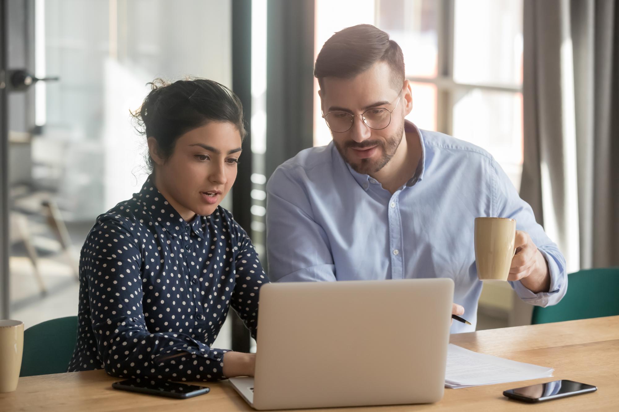 Two people sitting behind the laptop working together