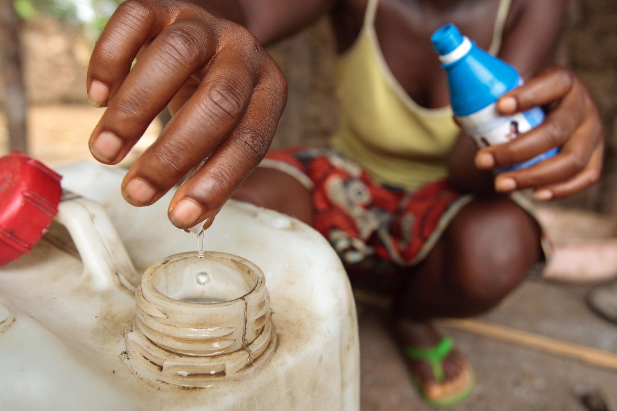 A woman uses a chlorine water treatment product to treat drinking water at home in the village of Kawejah, Grand Cape Mount county, Liberia on Friday April 6, 2012.