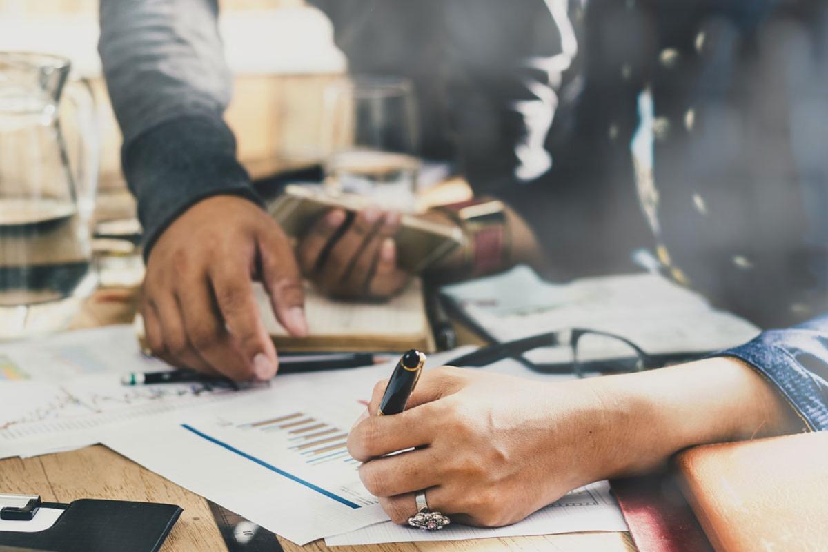 Male and female hands writing on a sheet of paper