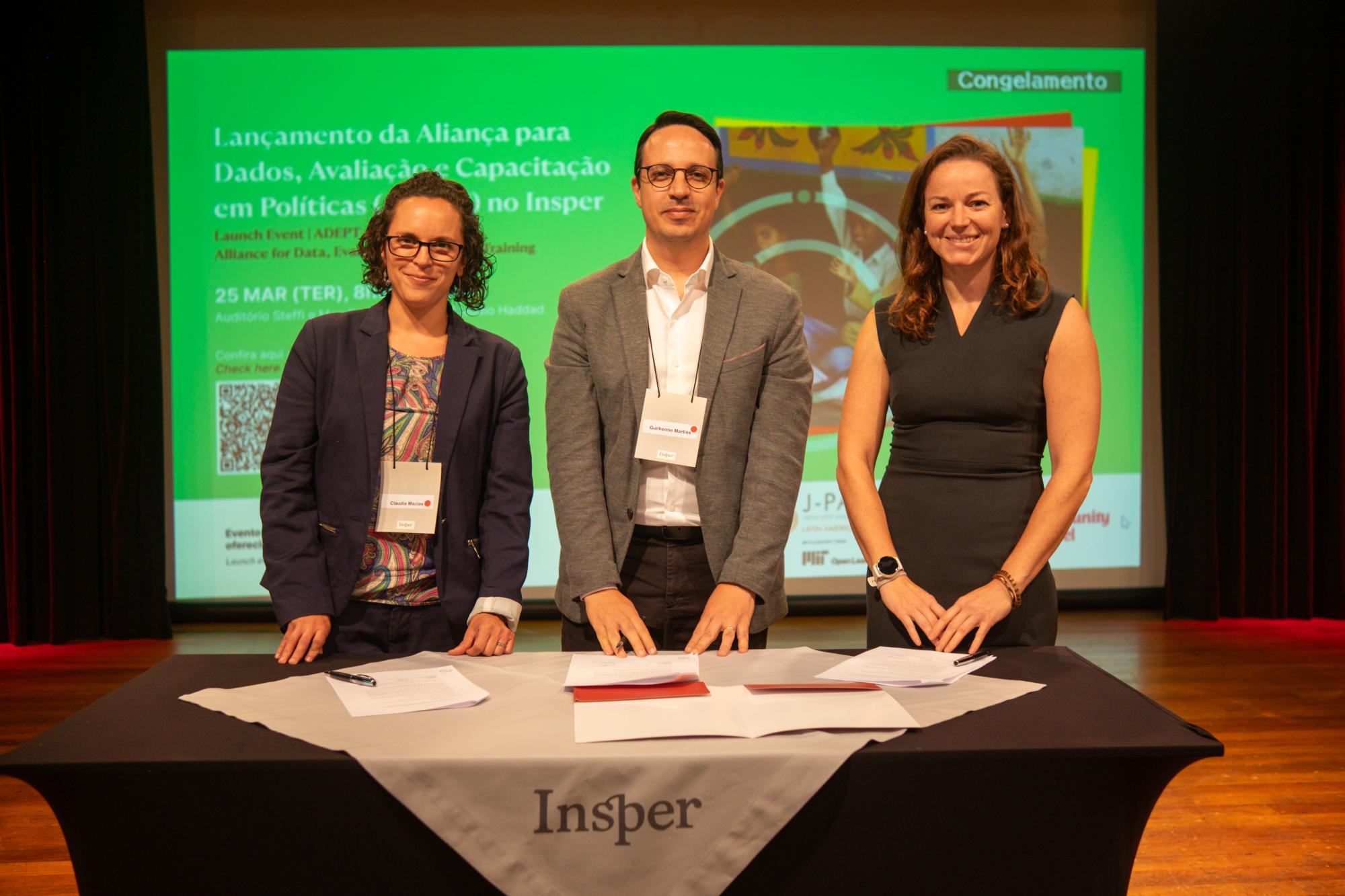 Three people stand in front of a table
