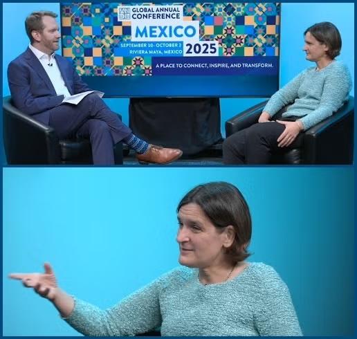 Esther Duflo sits in a blue shirt with a man in a blue suit, facing each other