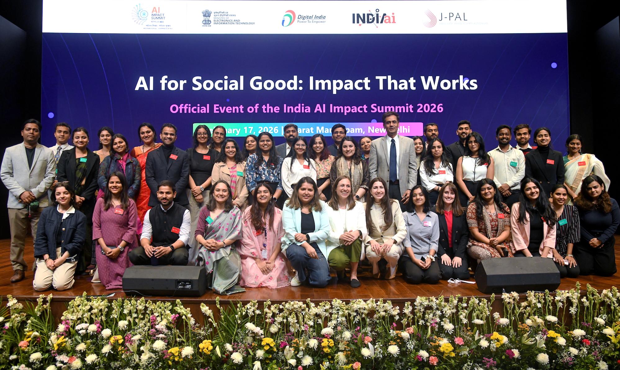 Group photo on main stage at 2026 AI summit in front of digital event backdrop