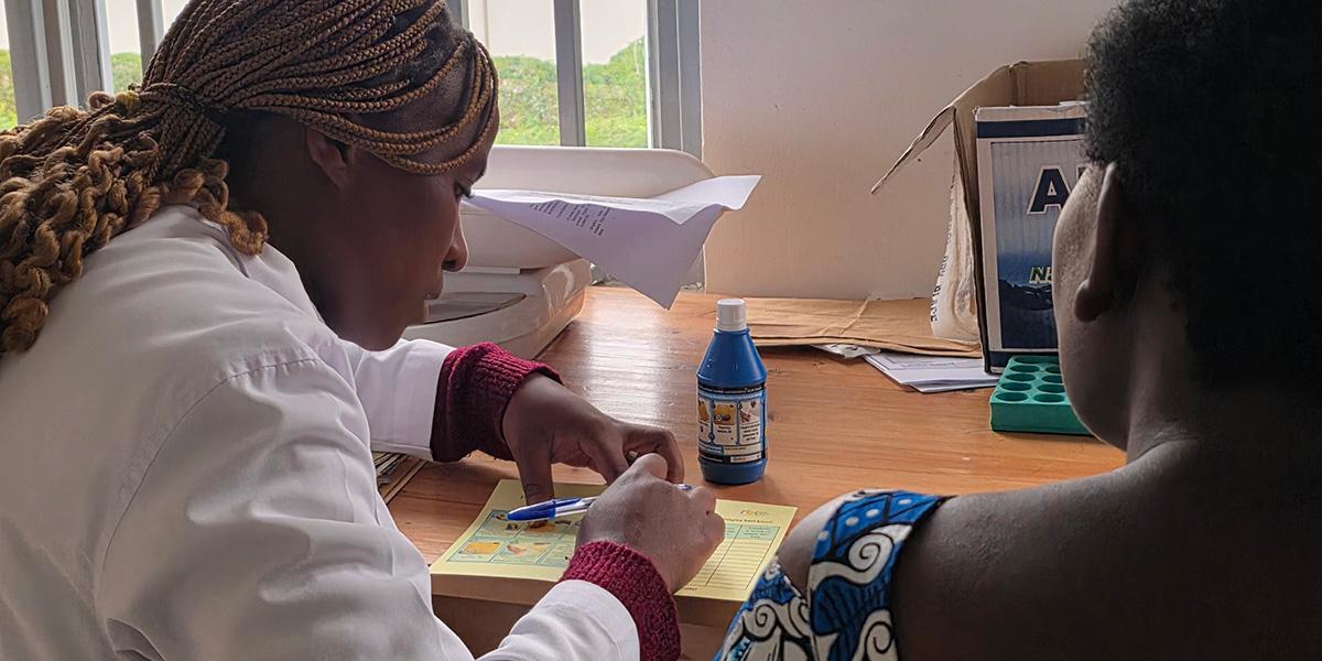 A nurse introducing the program to a beneficiary during a vaccination visit at Kinigi Health Centre.