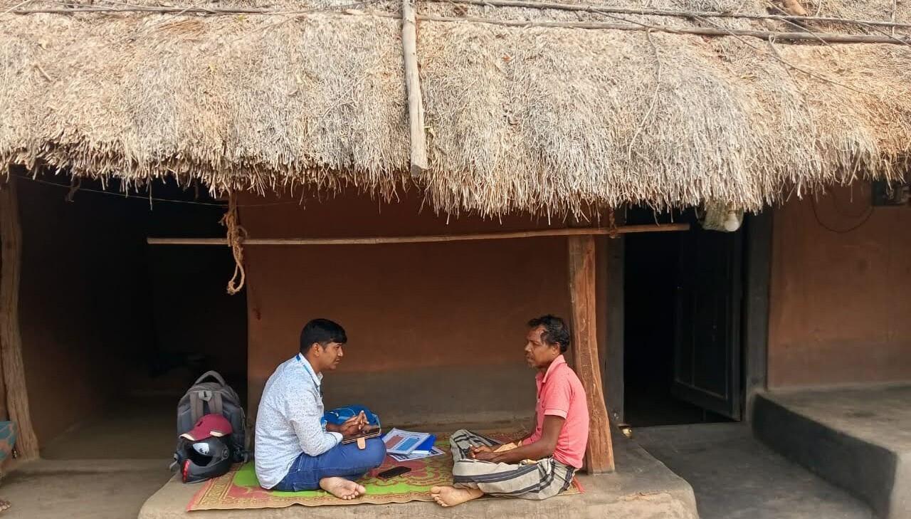 A field researcher conducting a household survey with a respondent outside his home.