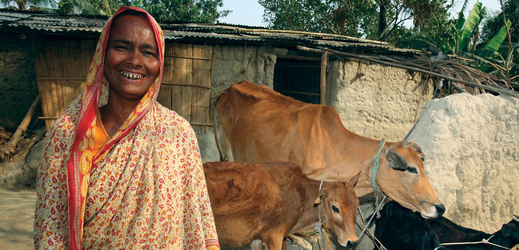 Smiling woman in a sari with two cows and a goat