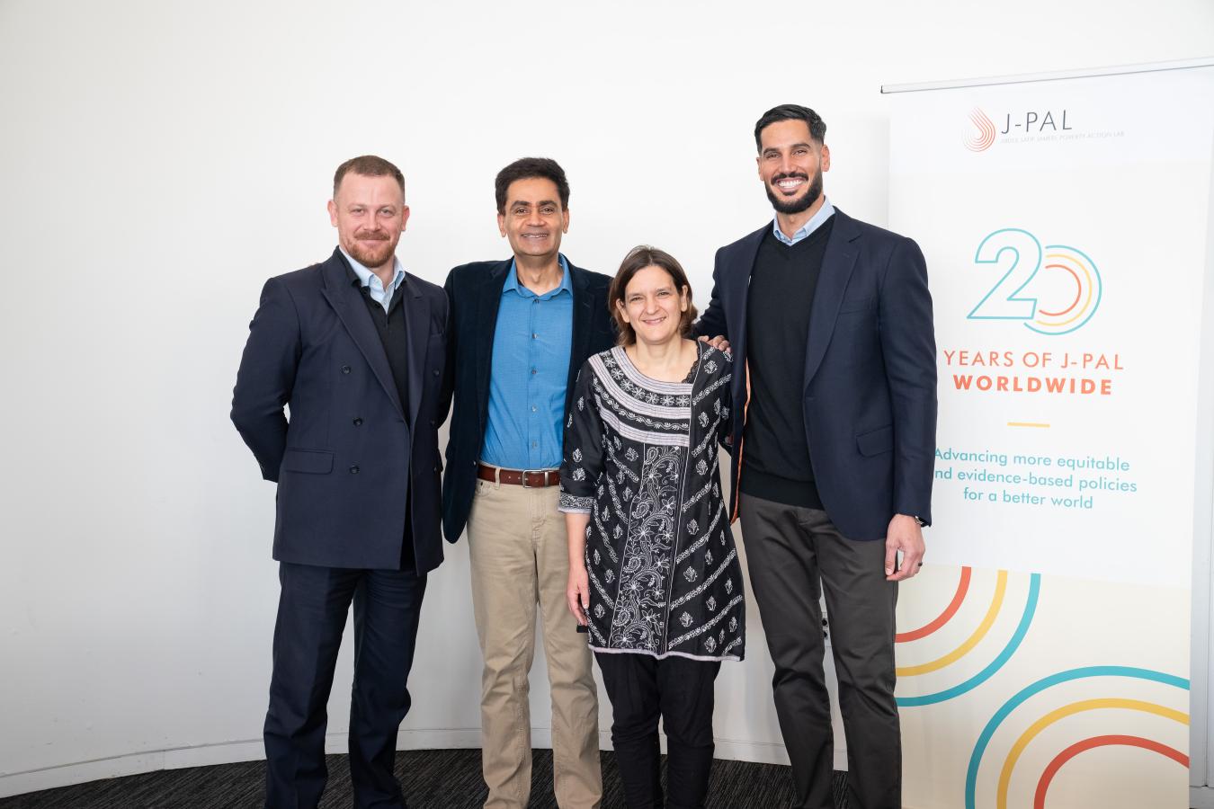 A group of three men and one woman stand together.