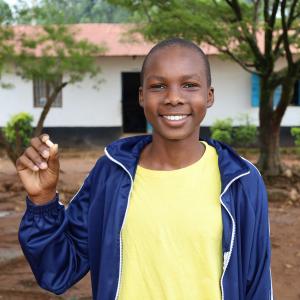 Young boy smiling while holding a pill