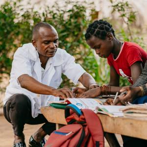 A teacher leans down to support a female student