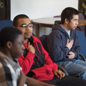 Three teenage boys hold their hands to their chest