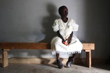 A young girl waits in a health center in Uganda.