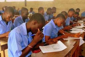 Teens in school uniforms work on assignment