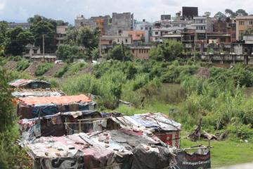 Houses made from tarps and wooden poles on the outskirts of a city