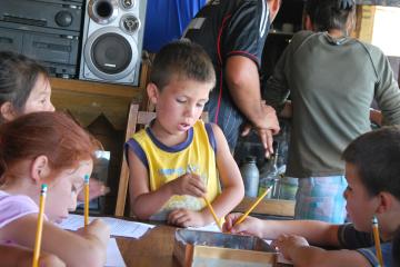 three children holding pencils and working on assignment