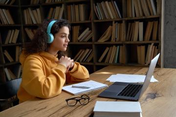 student wearing headphones sitting in front of a laptop