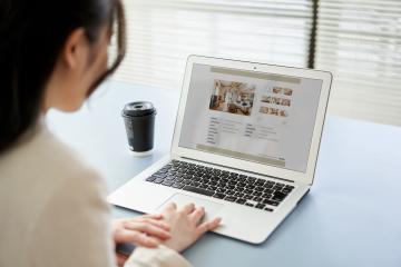 A woman looks at apartment listings on a laptop.