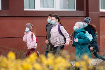 Children students in medical masks leave the schoo