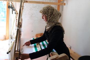 Woman with headscarf works on loom in textiles shops in rural Morocco