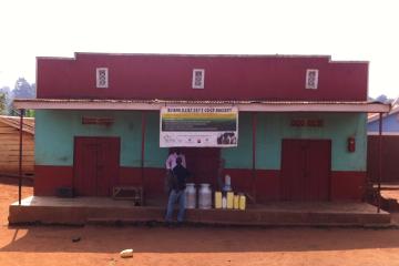 Farmers with milk jugs in front of the Buikwe Dairy Cooperative. 