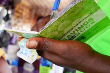 Hand holds a savings book and cash