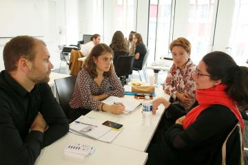 A group of people sit around a table discussing.