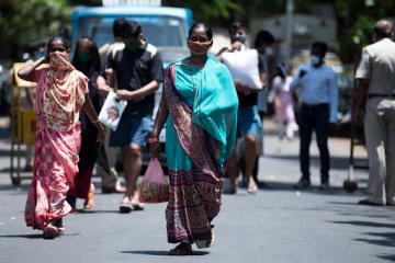 Women walk down a street wearing face masks