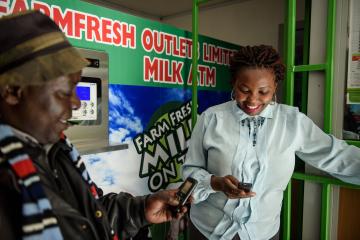 A man and woman use their phones for a mobile money transfer