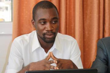 A close-up of Kodjo Aflagah speaking while sitting at a table.