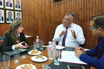 Juliette Keeley sits with two men at a table, discussing.