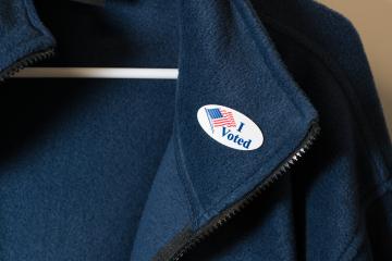 An "I voted" sticker with an American flag on a blue jacket